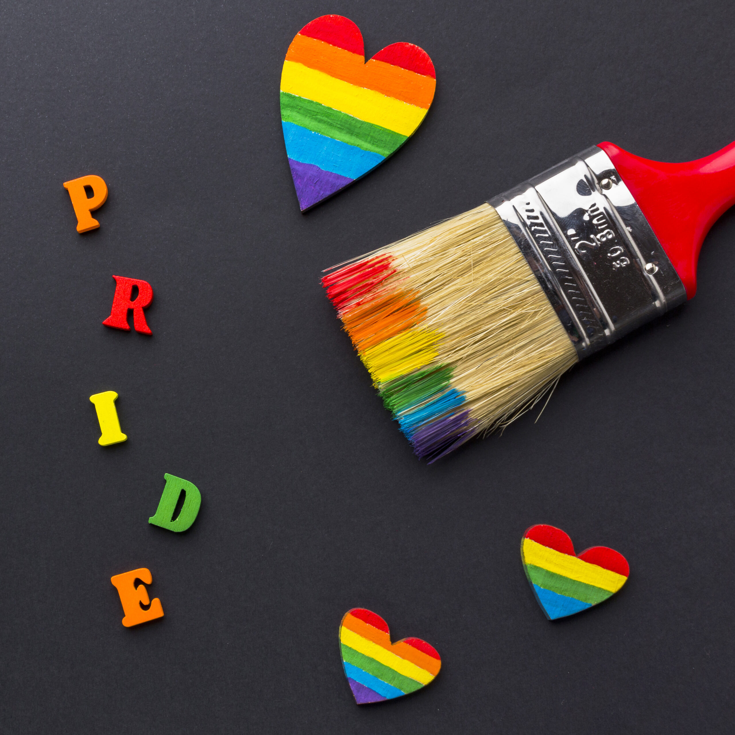 close up paint brush with rainbow hearts